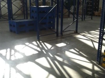 Casse blu impilate e scaffalature in un magazzino di Torino illuminato dal sole, lavoro di facchinaggio - MYA Traslochi